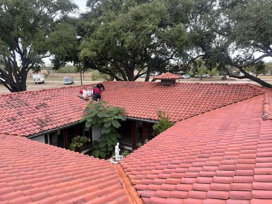 Crew repairing a red clay tile roof around a courtyard