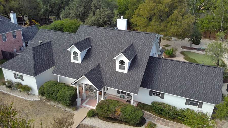 New gray shingle roof with two dormers on a white brick home