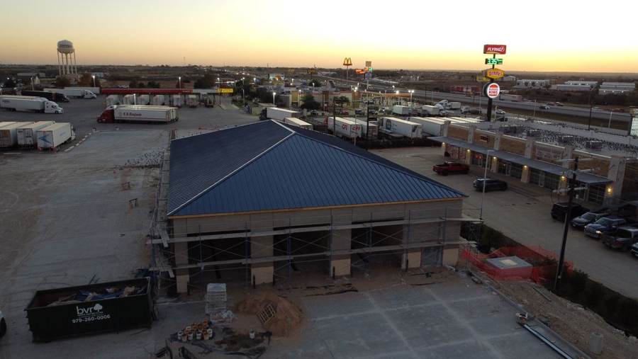 Blue standing seam hip roof on a new commercial building at dusk