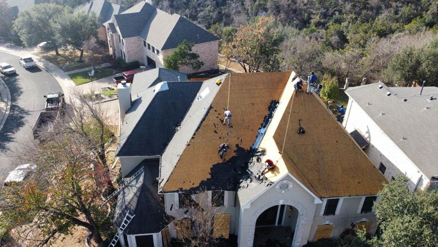 Crew tearing off an old shingle roof down to the decking