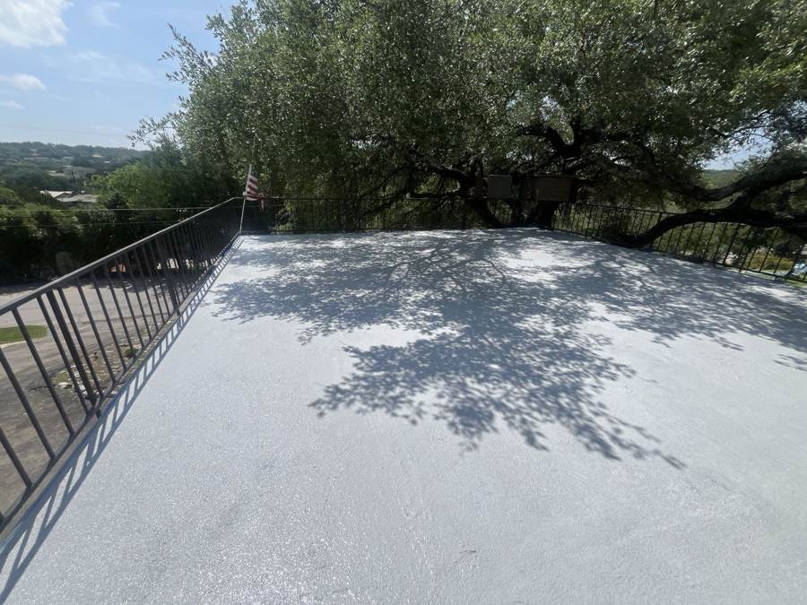 Freshly coated flat roof deck with iron railing under an oak tree