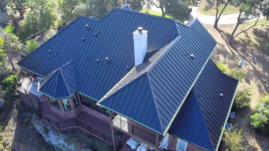 Black standing seam roof on a brick home with a wraparound deck
