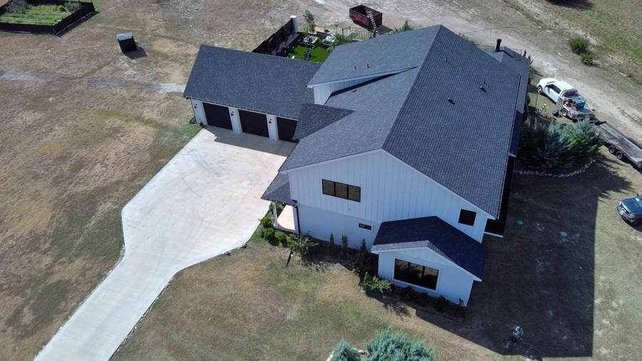 New charcoal shingle roof on a modern white farmhouse