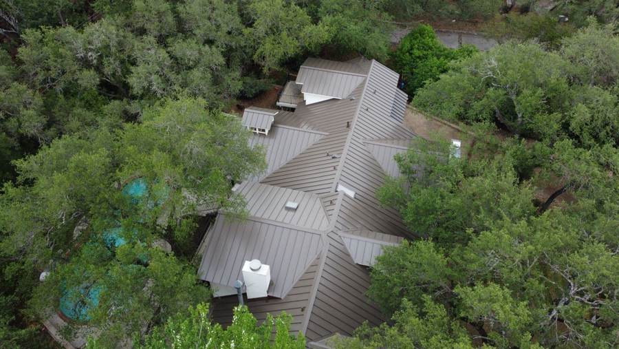 Aerial view of a bronze metal roof on a home in the woods