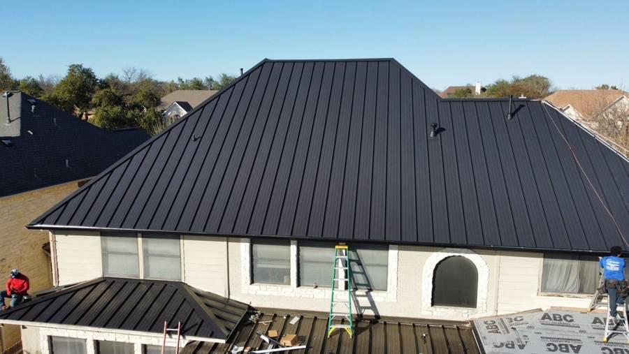 Black standing seam hip roof with a lower metal porch roof