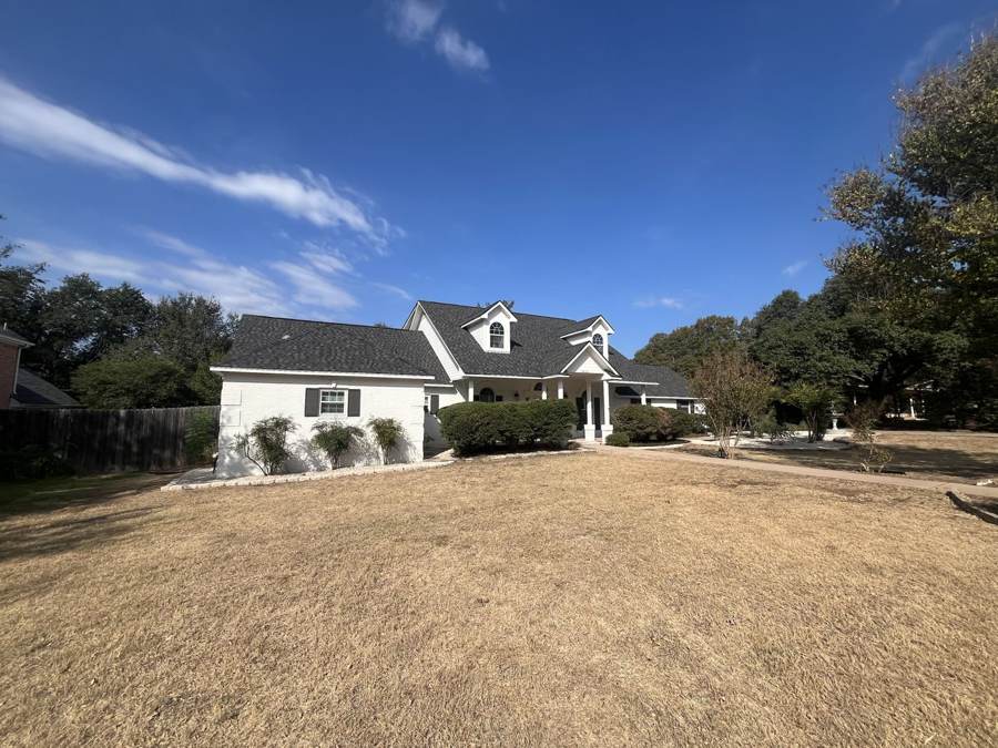 Street view of a white brick home with a new charcoal shingle roof