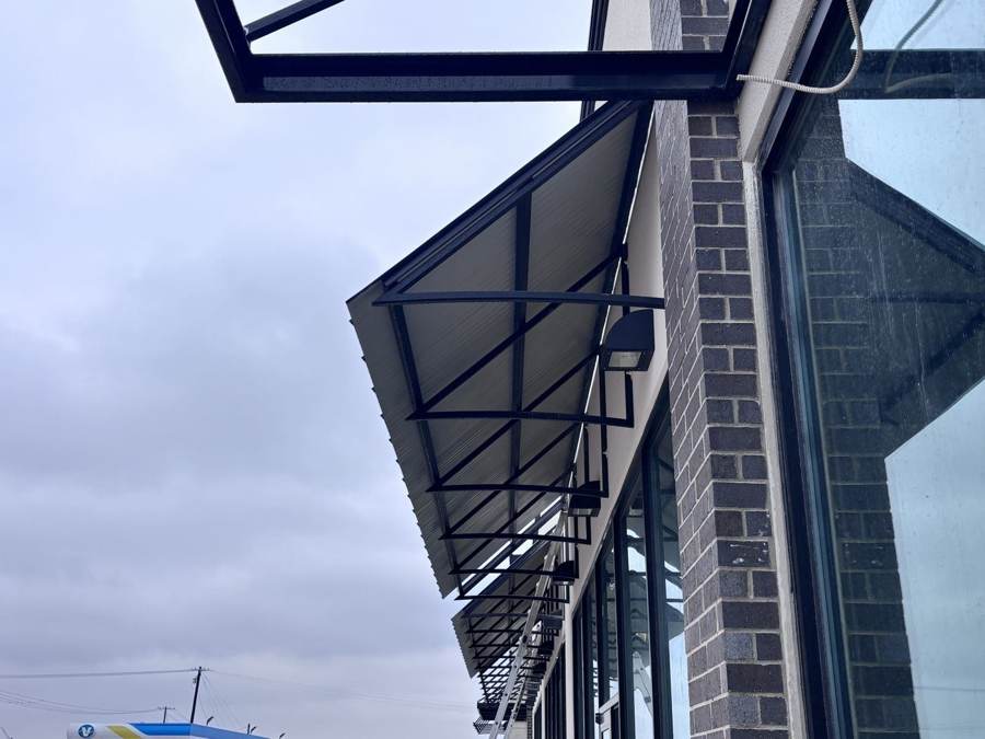 Metal awnings on steel frames along a brick storefront