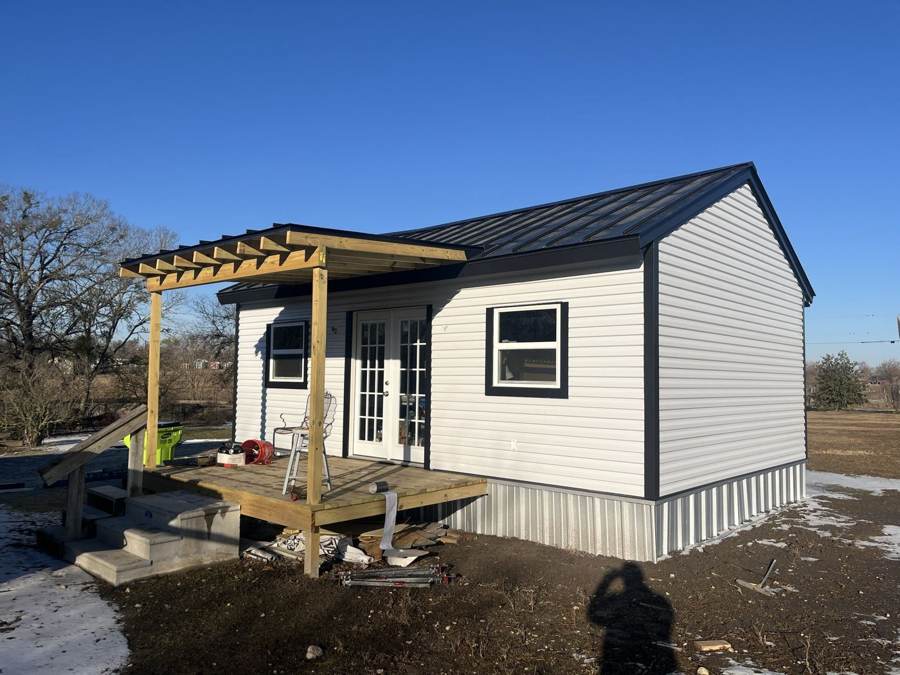 Small new building with black metal roof, siding and a porch