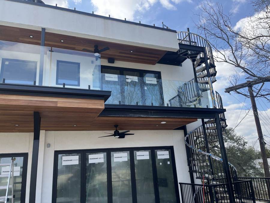 Glass railing balcony beside a black spiral staircase